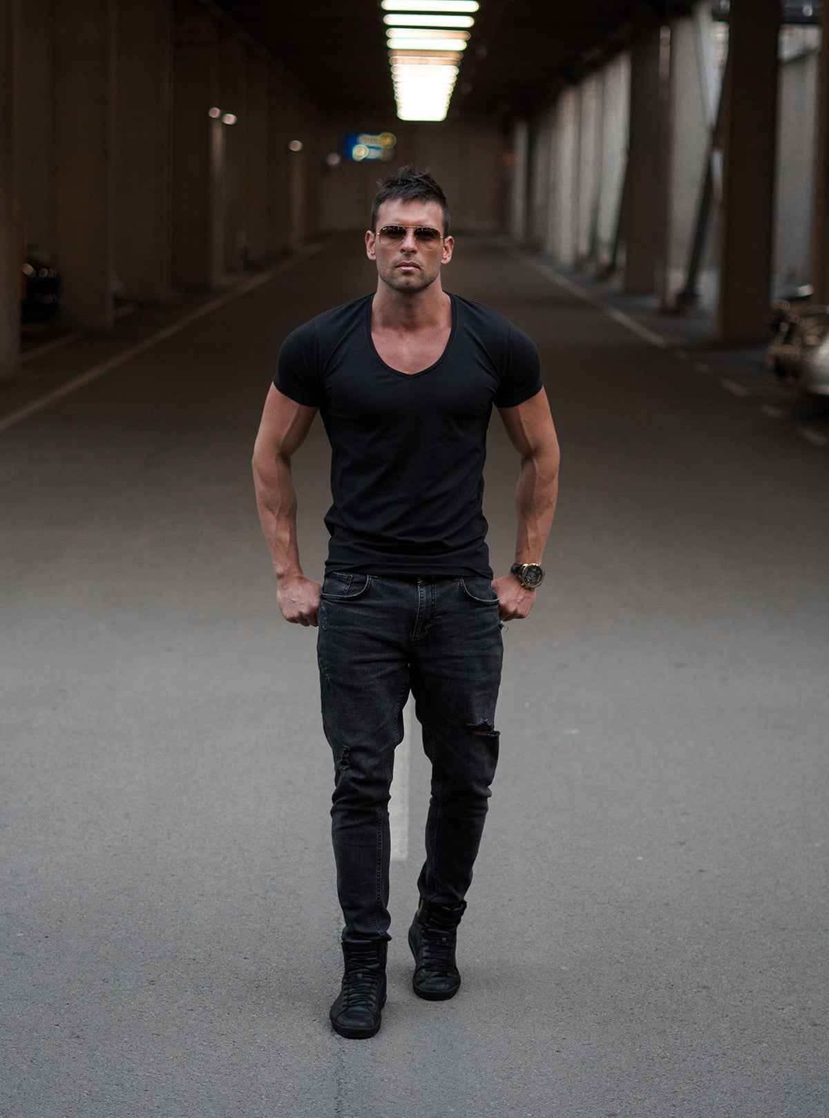 Man wearing a trendy black deep v-neck t-shirt and black pants in urban area