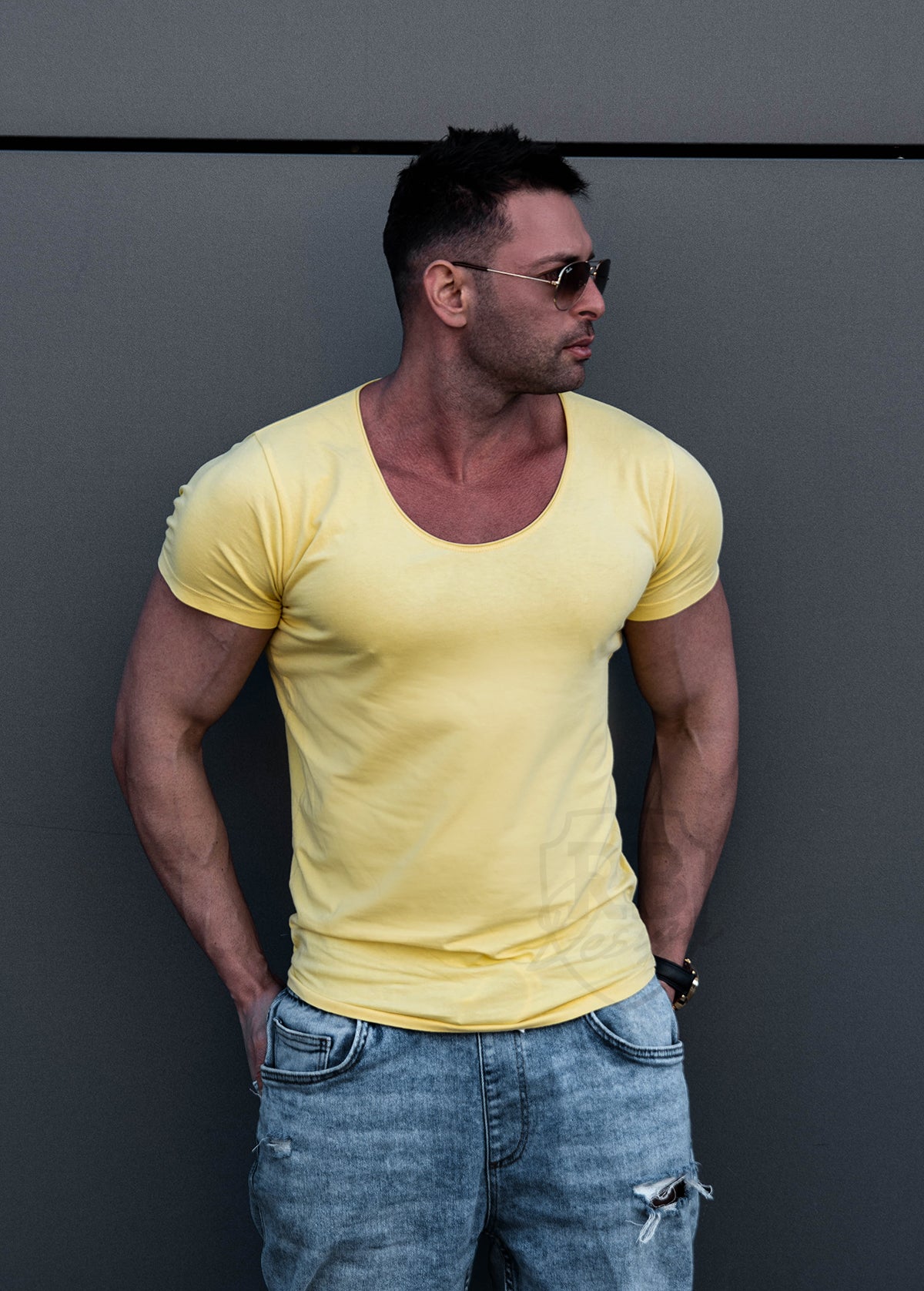 Men wearing trendy fashion scoop neck yellow t-shirt on clear metal wall